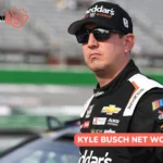 Kyle Busch net worth photo, driver in Cheddar's Scratch Kitchen racing suit standing trackside