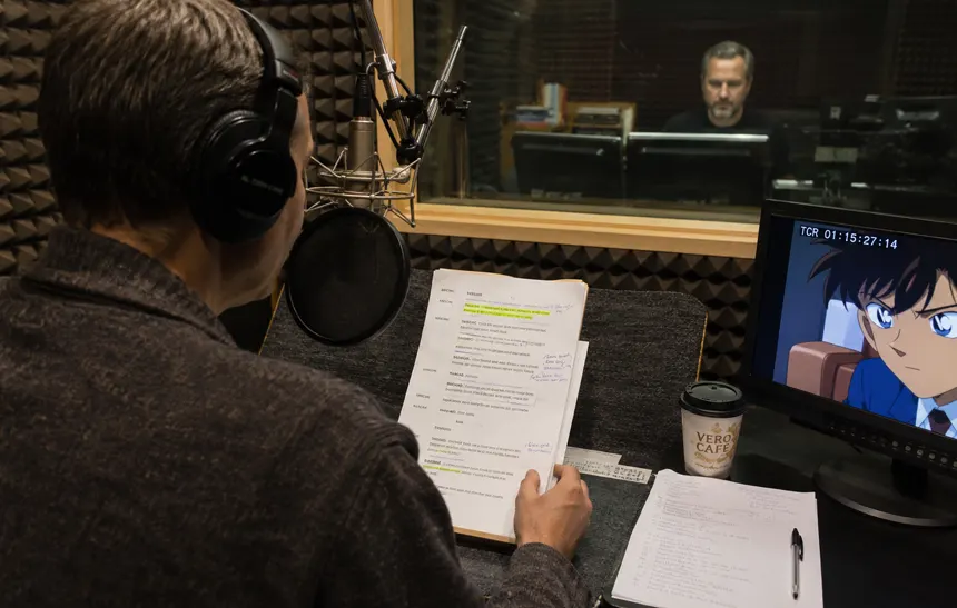 Voice actor recording Lithuanian anime dialogue inside a professional dubbing studio.