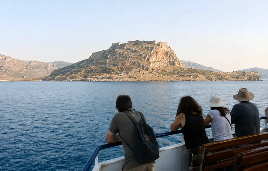 Ferry approaching Gramvousa Island with the Venetian pirate fortress visible above the cliffs in Crete, Greece.