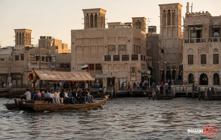 Traditional abra boat crossing Dubai Creek near historic Al Fahidi buildings in Old Dubai.