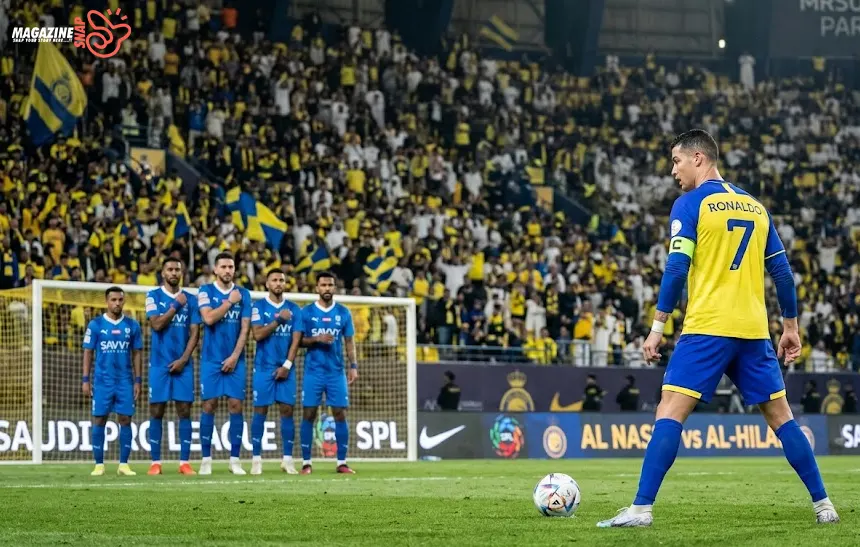 Cristiano Ronaldo standing over a free kick for Al Nassr during a Saudi Pro League match at night.