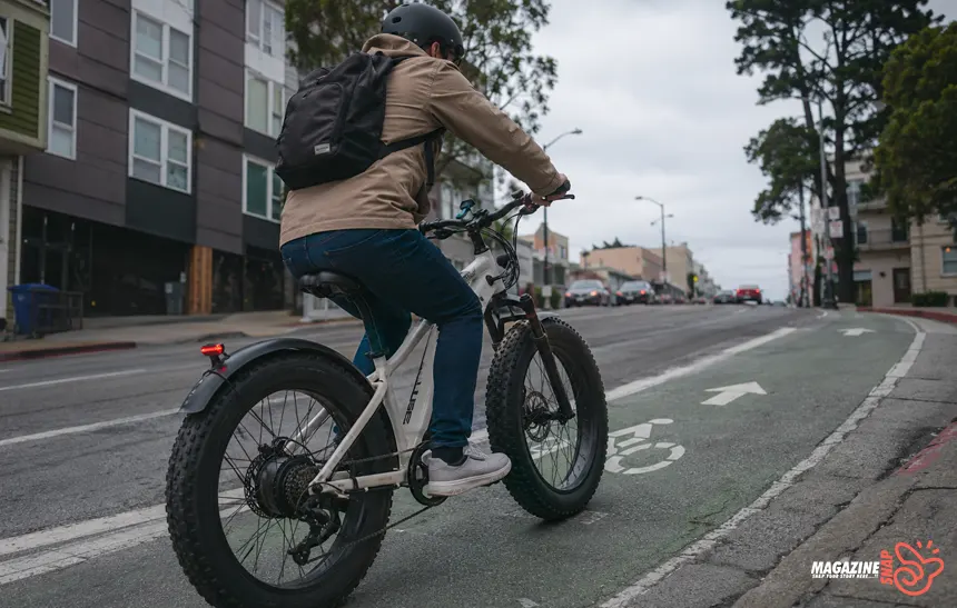 Rider climbing a steep city street on a fat tire e-bike with wide tires and natural morning light