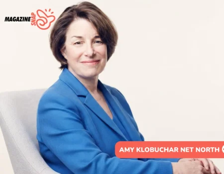 Amy Klobuchar smiling in blue blazer, seated in gray armchair for portrait