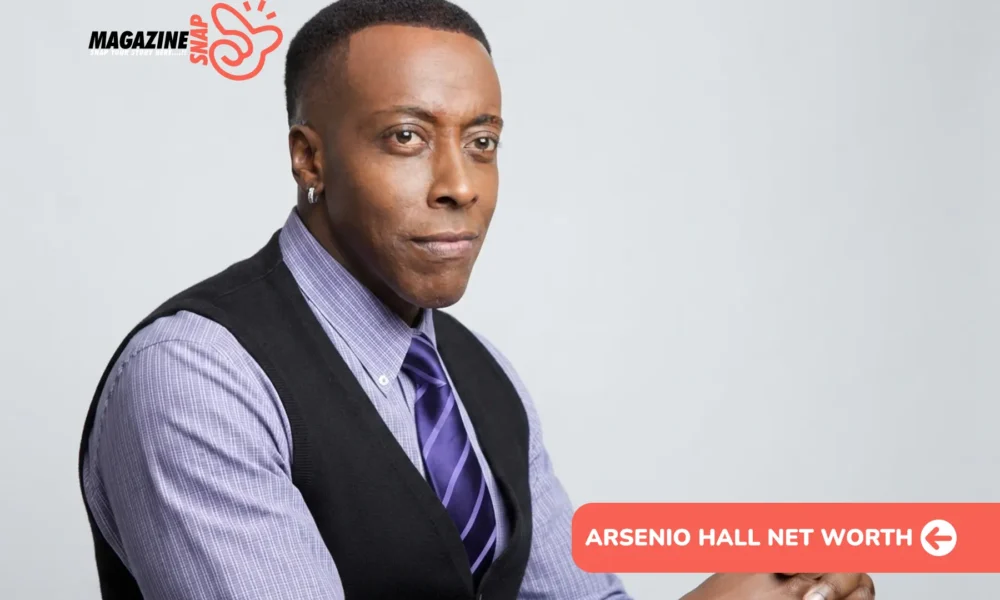 Arsenio Hall net worth photo: seated portrait in vest and purple striped tie