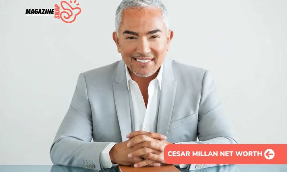 Cesar Millan Net Worth - gray-haired man in gray suit smiling at glass desk with notebook