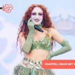 Chappell Roan performing live in green stage makeup and feathered costume