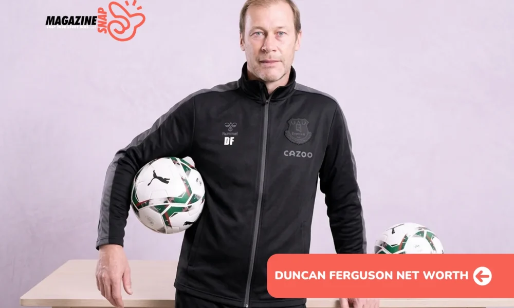 Duncan Ferguson in black Everton tracksuit holding a match ball beside a wooden table
