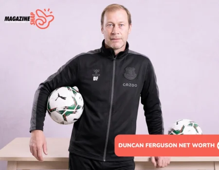 Duncan Ferguson in black Everton tracksuit holding a match ball beside a wooden table