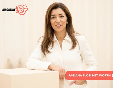 Fabiana Flosi smiling in a white blazer, leaning on a cream pedestal in a studio portrait