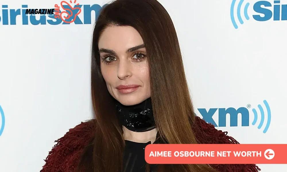 Aimee Osbourne in a burgundy jacket at a media event, pictured for the Aimee Osbourne net worth article.