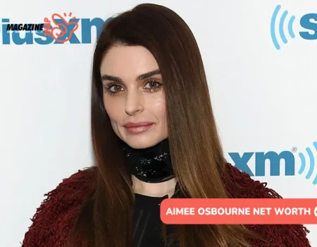 Aimee Osbourne in a burgundy jacket at a media event, pictured for the Aimee Osbourne net worth article.