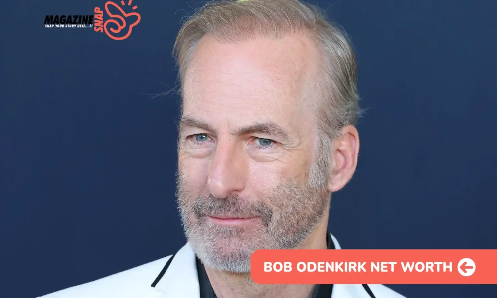 Bob Odenkirk in white blazer and black shirt against navy backdrop, bob odenkirk net worth article