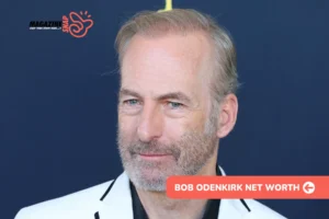 Bob Odenkirk in white blazer and black shirt against navy backdrop, bob odenkirk net worth article
