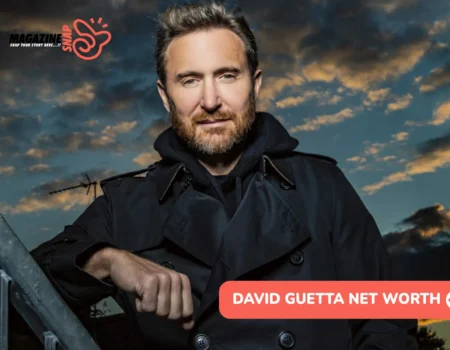David Guetta net worth leans on a rooftop railing at dusk in a dark coat for the article.