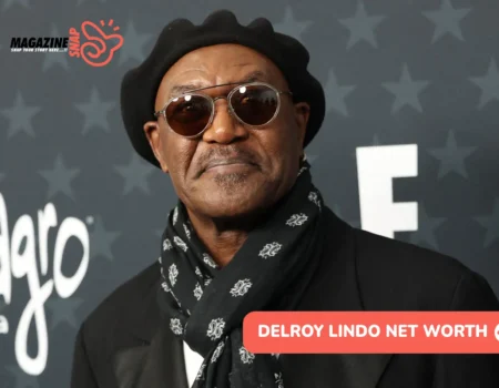 Delroy Lindo net worth article portrait: black beret, tinted glasses, and scarf at a red carpet event.