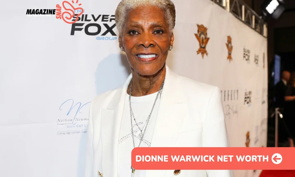 Dionne Warwick net worth smiling in white blazer at red carpet backdrop for Dionne Warwick article