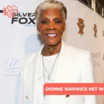 Dionne Warwick net worth smiling in white blazer at red carpet backdrop for Dionne Warwick article