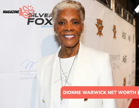 Dionne Warwick net worth smiling in white blazer at red carpet backdrop for Dionne Warwick article