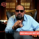 Ben Mallah net worth portrait, pointing at camera from a wood-paneled office desk.