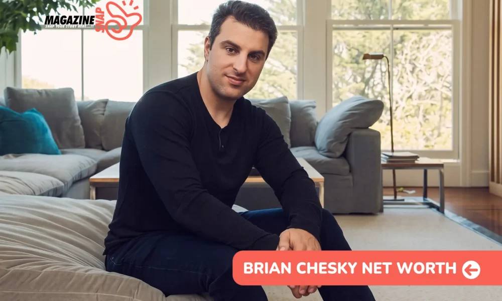 Airbnb CEO Brian Chesky sitting on a grey sofa in a bright living room, wearing a black long-sleeve shirt