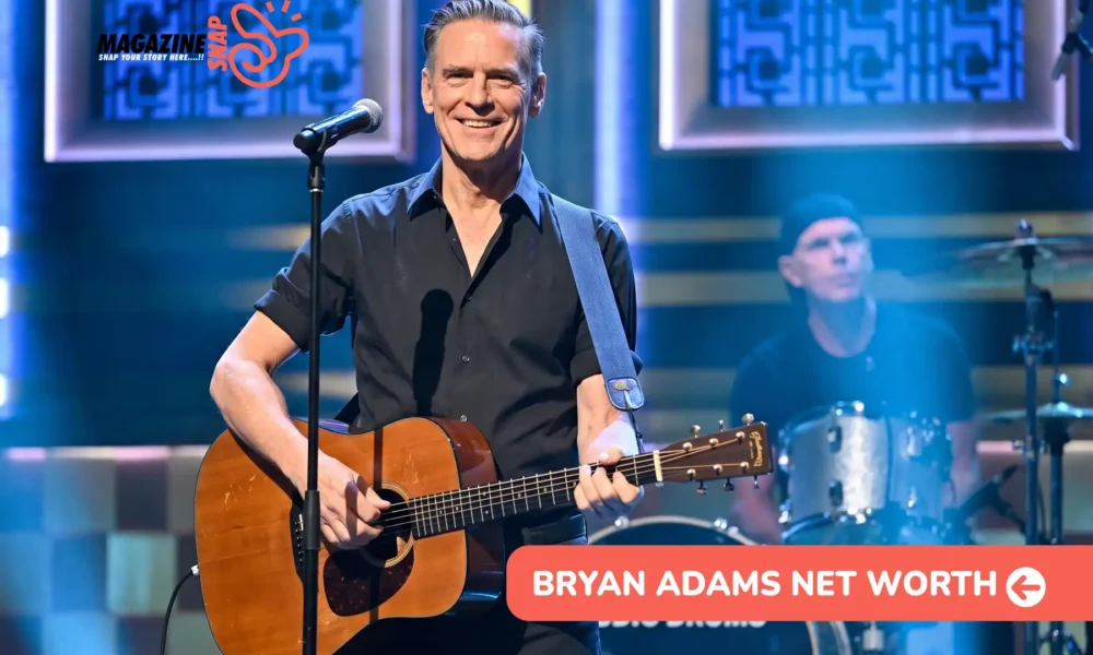 Bryan Adams net worth article photo: smiling guitarist in a black shirt at a microphone, drummer behind