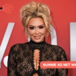 Blonde-haired Bunnie Xo smiling in a black lace top against a red backdrop, for Bunnie Xo net worth article