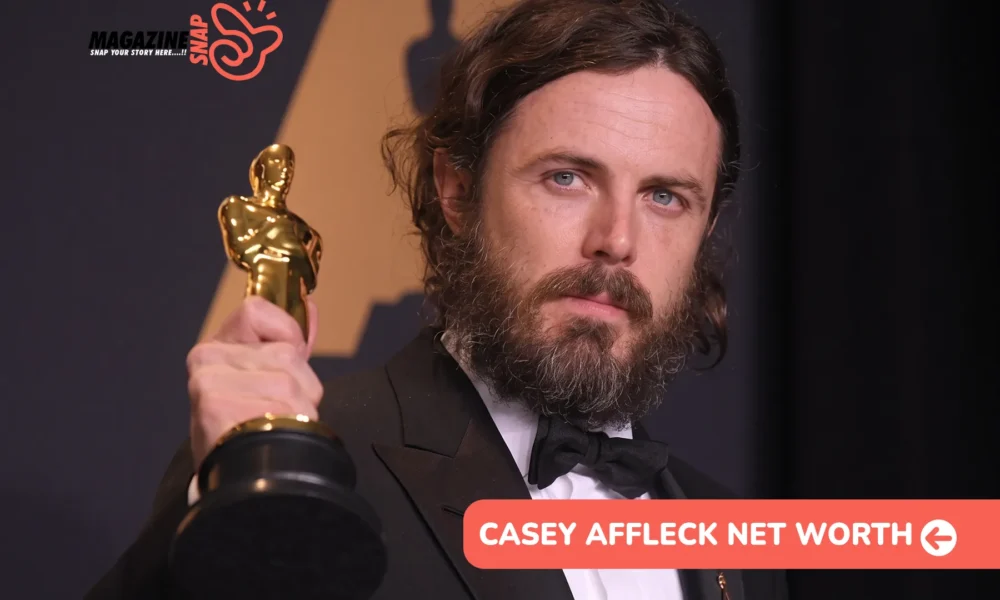Casey Affleck net worth article: bearded actor in a black tuxedo holding a gold Oscar statuette