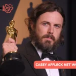 Casey Affleck net worth article: bearded actor in a black tuxedo holding a gold Oscar statuette