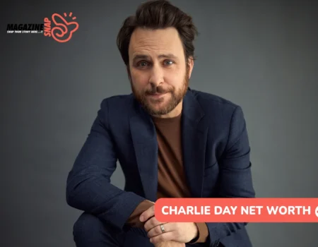 Charlie Day net worth article portrait of a bearded man in a navy blazer against a plain gray backdrop