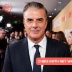 Chris Noth in a navy suit and polka-dot tie on a red carpet for Chris Noth net worth article, photographers behind