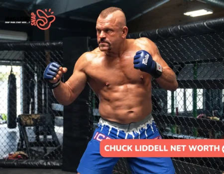 Chuck Liddell net worth article photo: fighter in blue gloves and shorts in a fighting stance beside a cage