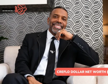 Creflo Dollar net worth article portrait of him smiling in a black suit and tie, seated in a striped armchair